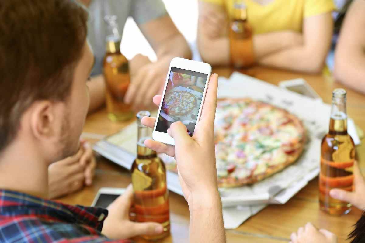 Ragazzo fotografa la pizza con il telefono
